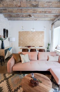 To make the space feel brighter, all of the walls—even bricks—are painted white, which contrasts with the raw brick ceiling and original brown tile floors. The Recast Plus sofa bed, with a pink hue that echoes the brick ceiling, is from Innovation Living. The blown-glass Gordiola pendants are a design the resident saw in a Mallorca hotel that Bloomint designed.