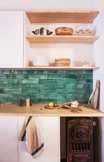 An original iron boiler the designers discovered during the renovation was kept in the kitchen as decoration. The counter is white pine, and the green tiles were sourced from Can Benito a studio in Mallorca. 