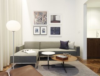 The living room features a 12-foot-high ceiling, which drops to 8.5 feet in other areas of the apartment—an design feature architect and resident Christopher Kitterman used to organize the space. Behind the curtain, sliding glass doors open to a small terrace. The artwork includes a pair of Cindy Sherman prints, a framed Hermès scarf, and two of Kitterman's own photographs.