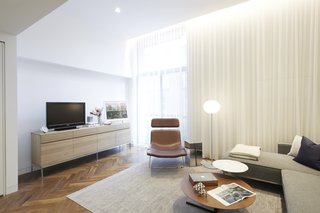 The living room furniture sticks to a soothing palette. The sectional is by Gus, the brown leather Spring chair is by Erwan Bouroullec for Cappellini, the silver side table is from Design Within Reach, the Glo Ball floor lamp is by Jasper Morrison for Flos, and the Bob tables are by Jean-Marie Massaud for Poltrona Frau. A photograph by the architect rests on a credenza from ABC Home, the same source for the rug.