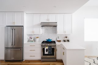 Sustainability is the Centerpiece of This New Austin Development - Photo 6 of 6 - The bright white kitchen is accented with metallic door pulls and a marble tile backsplash.