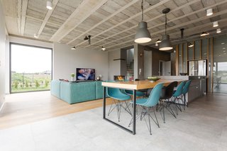 Rarely Do Family Homes
Look So Raw - Photo 1 of 3 - A mix of DSW and DSRA Eames Plastic Side Chairs from Vitra are seated at the dining table, which extends from a steel countertop. 