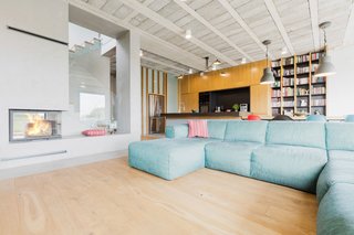 Rarely Do Family Homes
Look So Raw - Photo 2 of 3 - A concrete fireplace sits at the intersection of the staircase and the living room. The sofa is from MOMA Studio and the chandelier is a MCL-R3 lamp by Serge Mouille. 