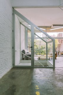 Brazilian architecture firm Pop-Arq flipped a dark industrial space in Buenos Aires into a bright split-level office for motion graphics studio ELOISA. A new glass enclosure for an existing spiral staircase provides acoustic insulation and a dimension of privacy without blocking light from the floor-to-ceiling windows. 