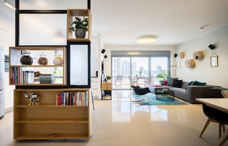 The 1,400-square-foot apartment, located in in a 21-floor high-rise, features a custom shelving unit/room divider by Greenbox Studio, which separates the living area and kitchen. 
