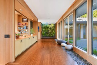 A Quintessential Midcentury Home Goes LEED Platinum - Photo 2 of 5 - The Mexican river rocks that hardscape the outdoors continue in the interior hallway, which connects the bedroom and living spaces. The green wall system is by Woolly Pocket. The flooring is Ecotimber strand-woven bamboo. 