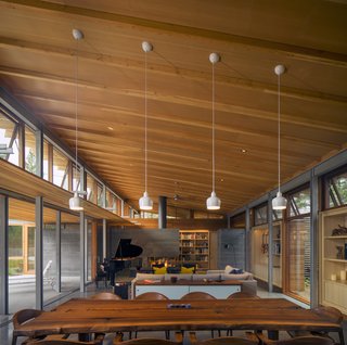 Honest materials appear throughout this Los Altos, California, home. In the double-height living area, Mantis chairs by BassamFellows surround a custom live-edge dining table, fashioned from an old Claro walnut tree with help from Menlo Hardwoods. 