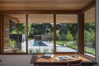 Looking out from one of the home offices, a board-formed concrete garden wall and linear pool draw the eye toward a guesthouse. 