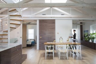 Natural light entered the original apartment through three sides plus a skylight. A wall that blocked the passage of light between the bedroom and main living area was replaced with a custom 10-foot-long barn door, which is outfitted with coat hooks from Design Within Reach that the residents use as pulls. The dining table is from Mohr McPherson. 