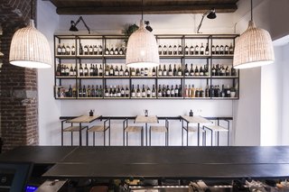 Bringing a Taste of
Sicily to Milan - Photo 4 of 5 - Shown here is a frontal view of the Studio DiDeA-designed bar stools and tables that are connected to a sliding track system. Above these furnishings, modular shelves feature a selection of wines available for sale. 