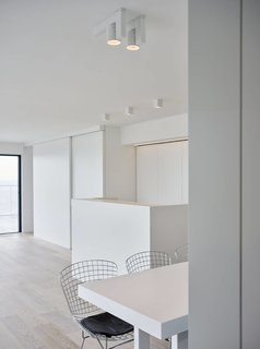 Knokke is a minimal space created by Belgium-based designers minus. The space is characterized by a wrap-around balcony that overlooks the ocean. Panoramic windows span both walls of the main living area to take advantage of the view as well. Both the kitchen and entertainment unit are concealed by a series of sliding doors. An array of cubic spot lighting provides additional illumination for areas such as the kitchen counters, dining table, and sofa.