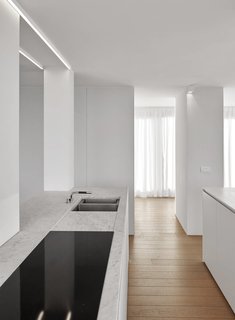 De Panne is a minimal space located in Belgium, designed by minus. The space features sprawling ocean-front views, which the architects wanted to capture by providing panoramic windows throughout the space. Natural materials dominate the space, including accent materials such as marble and steel. The main living area has an open floor plan that connects with the dining and kitchen area. Large glazings provide abundant natural light during the day, some of which slide open to provide access to the balcony.