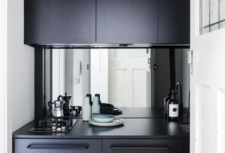 In a compact apartment in Australia, the kitchenette uses a mirrored take on the glass backsplash to bring in an element that would reflect light (and views). The mirrored backsplash is relatively easy to clean with the right cleaning tools, but might drive a clean freak a little crazy. Regardless, it's a great contrast to the dark cabinets.