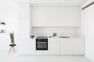 These 30 White Kitchens Are Anything But Ordinary - Photo 16 of 30 - A minimalist interior located in Tel-Aviv, Israel, has been designed by Yael Perry. The apartment was renovated and includes a bright living space, kitchen, and one bedroom, along with a wide bathroom. The designer, who wanted to provide a unique aesthetic that also made the space feel more spacious and bright, chose to design the apartment in one shade of color: white.