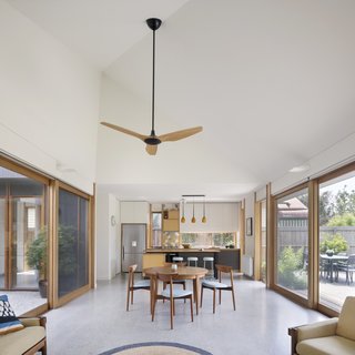 Blackbutt window treatments and a polished-concrete floor unify the kitchen, dining, and living areas on one end of the courtyard. A Haiku ceiling fan by Big Ass Fans provides extra air. 
