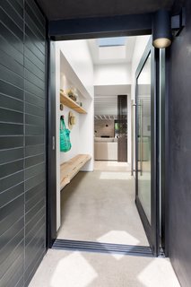 Benjamin Moore's "Swiss Coffee" was used in the entryway, which features a custom bench and shelf made of unfinished oak by Anderson Plywood. 