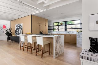 Blu Dot stools line up against Calacatta Gold Extra countertops. The custom cabinetry was outfitted by Semihandmade with Ikea cabinet bodies. 
