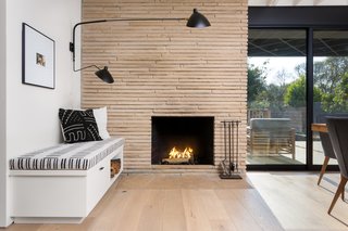 The original fireplace was resurfaced using Colorado Buff Ledge stone, which offsets the black-and-white shades of the custom bench and Stilnovo sconce. 