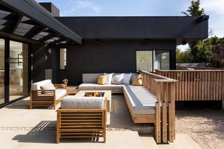 The wraparound porch is enclosed in custom unfinished spruce, and match the slated look of the World Market chairs. The owner says that her custom concrete fire pit has been a great place to entertain.