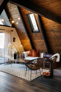 A 1970s A-Frame Cabin in Big Bear Is Brought Back to Life - Photo 4 of 12 - Picks from West Elm furnish much of the living space, including the chandelier, coffee table, and rug. A leather Article sofa sits next to a pendant light from Anthropologie. 