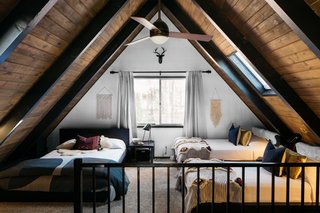 A 1970s A-Frame Cabin in Big Bear Is Brought Back to Life - Photo 10 of 12 - "We wanted to create a bohemian feel in the bedroom and the loft spaces," she says. "We went with a speckled carpet for the upper level and just let the textiles work their magic on the bedspreads and pillows." Macrame wall hangings found on Amazon complement the diamond-shaped detailing on the Anthropologie throws atop the twin beds. 