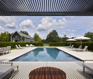  "It's a big property, so we had space to spread out," he says. "The pool is purposefully removed from the main house in order to make it feel like a destination." Ninix by Royal Botania furniture sits under Tucci umbrellas. 