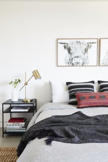 A Tim Gainey photograph of a Highland cow from Fine Art America sits above a red lumbar pillow by Amber Interiors and Restoration Hardware Bedding. 