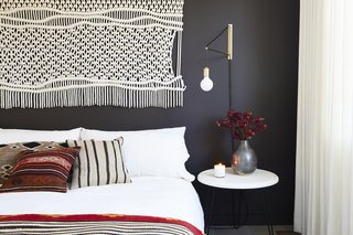 In the second bedroom, a macrame wall hanging and gold sconce were found at Etsy, which matches the sentiment of the DIY nightstand. Matteo bedding pops against the Midsummer Night wall color by Benjamin Moore. 