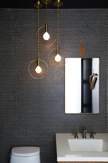 "We wanted a space to feel completely unique from the other rooms while still being a part of the overall palette," DeSanti says. Which room got the "jewelry box" feature they were envisioning? The powder room. It's outfitted with an organic Modernism mirror, Ladies and Gentlemen pendants, and penny rounds, of course. 