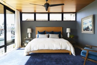 The master bedroom unites the rest of the home's shades and textures in a calm palette. The custom bed is centered above a Crate and Barrel area rug. As with most of the art in the home, the one hanging above on the right is from the owners' personal collection. 