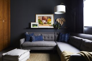 In the den, the Kendall Charcoal paint shade by Benjamin Moore is matched by the equally dark shade of the West Elm sofa. Artist Laura Buchan supplied the wooden sculpture, and the floor pouf was sourced from Porch in nearby Carpinteria. 