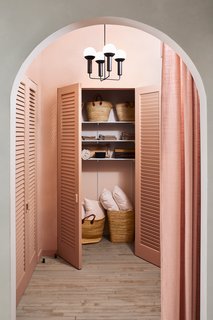 "The dramatically tall and wide arched entranceway with the modernized Louver closet doors reminds me of a 1930s Hollywood film set," Hesser says. The closets are used to store props for events and shoots, including lots of wine. 