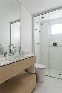 The main bathroom is unified with the rest of the home thanks to the same burnt cement flooring. A solid wood countertop was installed by Inovart Woodworking, and the adjoining white quartz countertop was picked from MSA Marmoraria. 