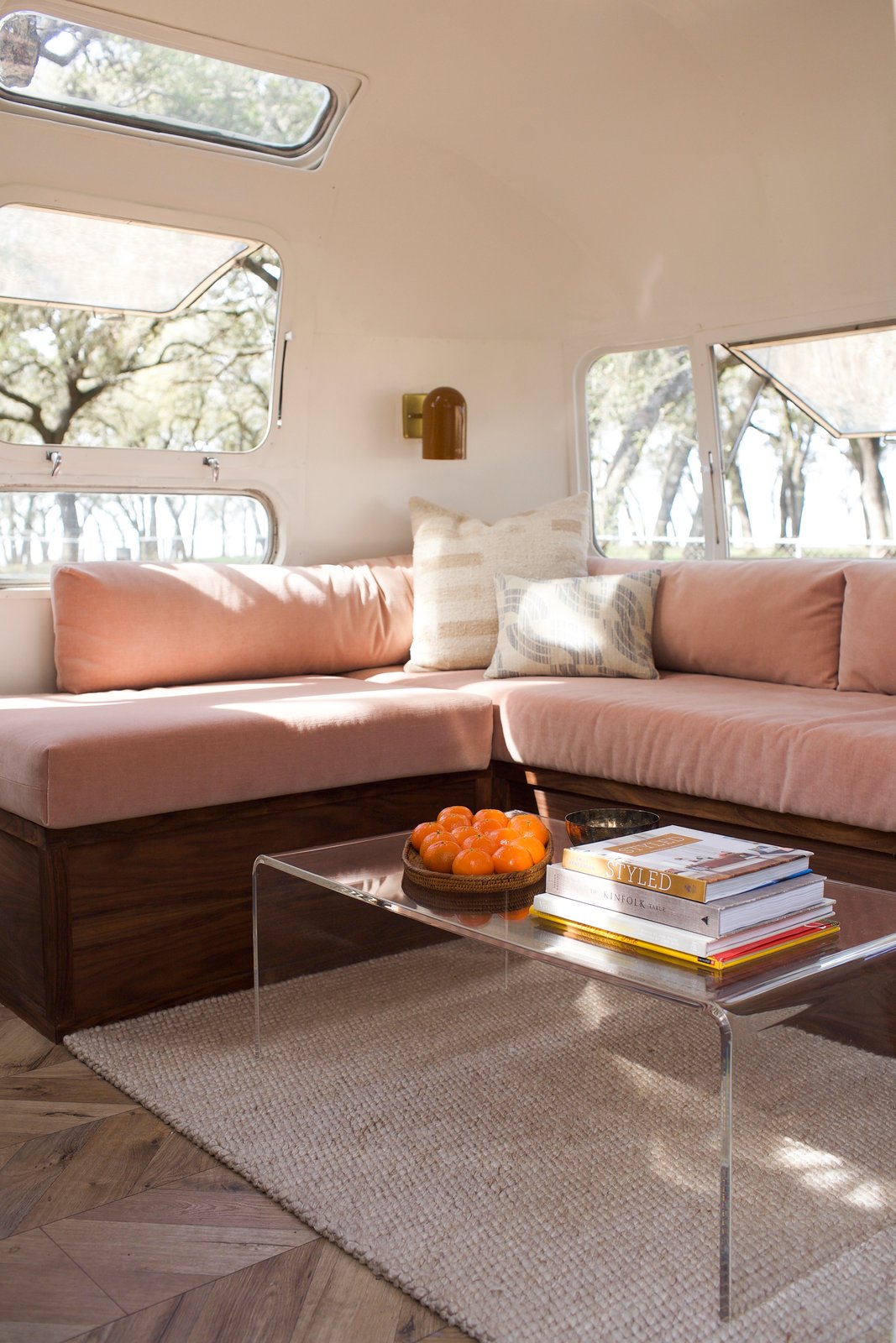 Storage under the blush-toned sofa makes it easy to keep the area neat. A CB2 coffee table sits above a Dash & Albert rug, and the sconces were sourced from Schoolhouse Electric. Kaindl flooring and Benjamin Moore's