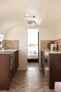 "You can absolutely have a large, functional kitchen with nine feet of counter space, plenty of storage, a deep sink, and gorgeous off-grid, yet completely functional and spacious appliances," Oliver says. "We didn’t have to sacrifice anything in this kitchen, and it turned out beautiful." Custom walnut cabinetry complements a Delta faucet, while a Dometic range and Isotherm fridge and freezer round out the space. 