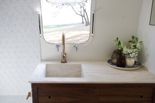 A detachable shower head in the bathroom makes dog-washing easier, and a composting toilet allows the owners to go off-grid for longer periods of time. Aside from that, walnut and marble accents—plus the same Corian Dune prima deep sink used in the kitchen—make the bathroom stylish, too. The shower tiles were found at Lowe's.
