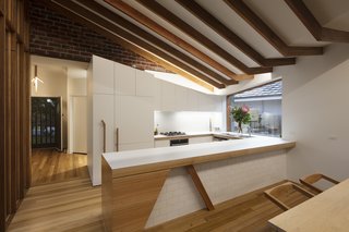 Custom woodwork on the kitchen cabinetry mirror the slant of the roofline. Recycled brick was used on the upper portion of the wall. 
