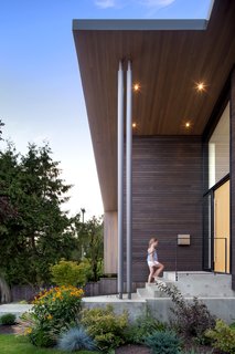 The exterior's many textures include stained western red cedar siding, a white oak veneer front door, and a concrete walkway. 
