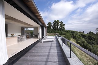 Mahogany decking continues onto this balcony, while a full-length slider makes it easy to fill the indoor spaces with fresh air. Curtains from The Shade Store provide privacy when needed. 