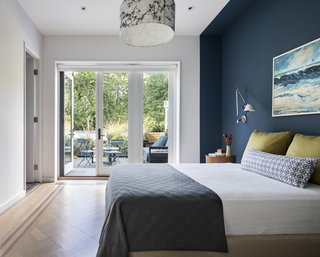 The home has two bedrooms; this master suite leads to a private deck. The bold accent wall complements the color in the dining room.