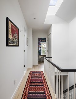 The "white, gray, and walnut" palette balances the owners' desire for bold shades. It's especially apparent in the upstairs hallway.