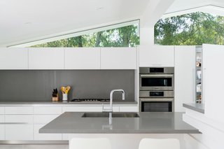 The sleek oven duo, aligned beautifully with clerestories above, sits flush with kitchen cabinetry.