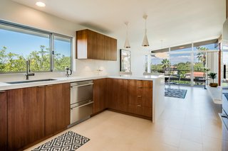 The updated kitchen features sleek walnut cabinetry, Fisher & Paykel appliances, Caesarstone countertops with a waterfall edge, and modern pendant lighting.