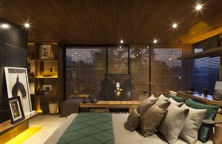 An Incredible Brazilian Home That Celebrates Art, Travel, and Nature - Photo 8 of 14 - Seamlessly connected to the living room without doors or dividers, the moody master bedroom is punctuated by collected art.
