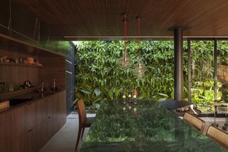 An Incredible Brazilian Home That Celebrates Art, Travel, and Nature - Photo 5 of 14 - Sliding glass walls tuck into the home's stone exterior, allowing the living space to be completely open to the lush vertical garden outside.