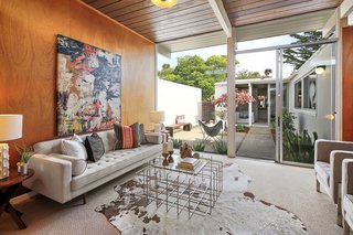 The living room has original wood paneling and floor-to-ceiling windows with courtyard access.