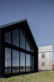 Between the front of the home (the "road side") and the rear of the residence (the "bay side"), there is a marked difference in the size and number of window openings. With so much glazing at the rear, "it is interesting to explore the intimacy of how you break up what is glass," says Adair. Kopp and Adair did this by creating more visible frames in the glass that would celebrate the structure, rather than make it disappear.