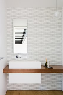 The second floor powder room reflects the glass bridge above.