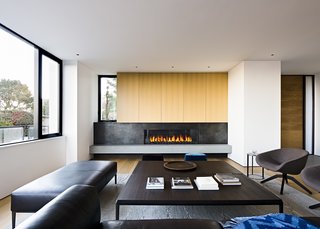 In the living room, rift cut white oak millwork marries wax steel detailing at the striking fireplace.