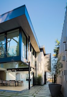 The home's main entry—two levels off the street—forces guests to get intimately acquainted with the steep topography of the site. Although the home's residents have the option to enter via garage and interior stair, guests instead travel up exterior stairs at the corner of the site, passing the planted neighboring lot to reach the home's front door.